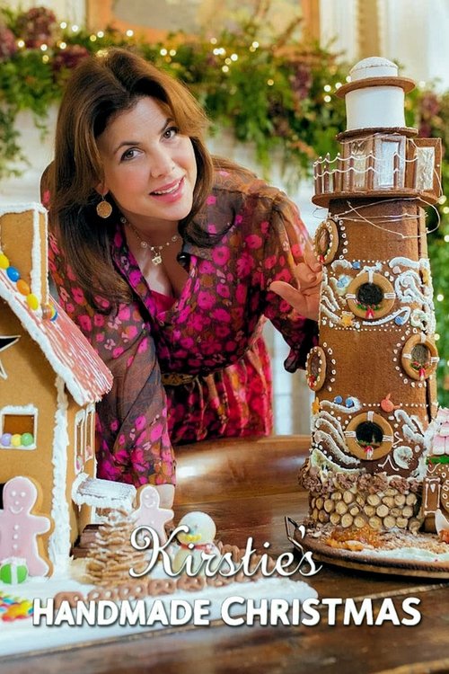A woman in a vibrant pink dress smiles warmly at the camera, surrounded by beautifully decorated gingerbread houses and festive ornaments. The warm, cozy atmosphere captures the joy of holiday crafting.