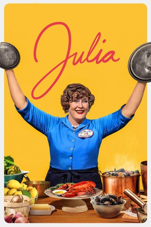 The poster features a cheerful woman with short brown hair in a bright blue chef's uniform, proudly holding up two large metal plates against a vibrant yellow background. She stands behind a table laden with colorful ingredients like lemons, tomatoes, and vegetables, suggesting a cooking show set...
