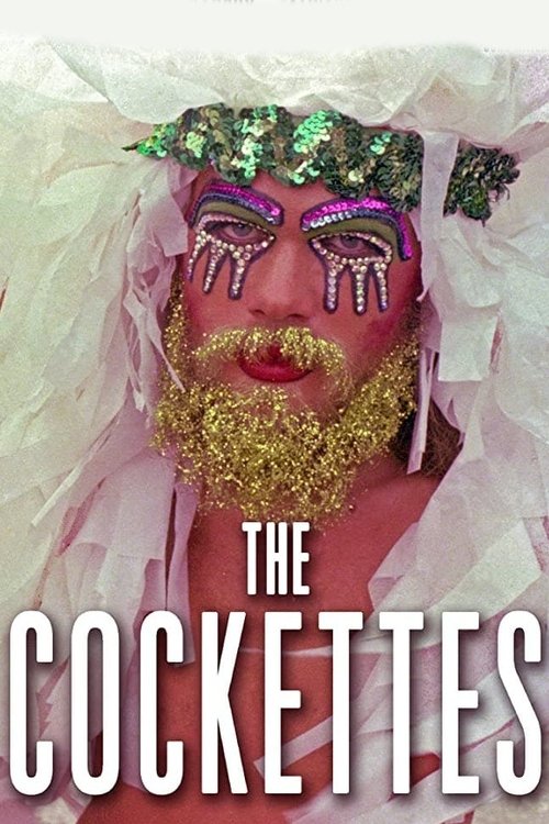 The poster features a striking close-up of a person adorned with elaborate makeup and a gold beard, wearing a festive crown of green and purple beads. The scene exudes a vibrant, carnival-like atmosphere, with the title "The Cockettes" prominently displayed in bold white letters at the bottom.