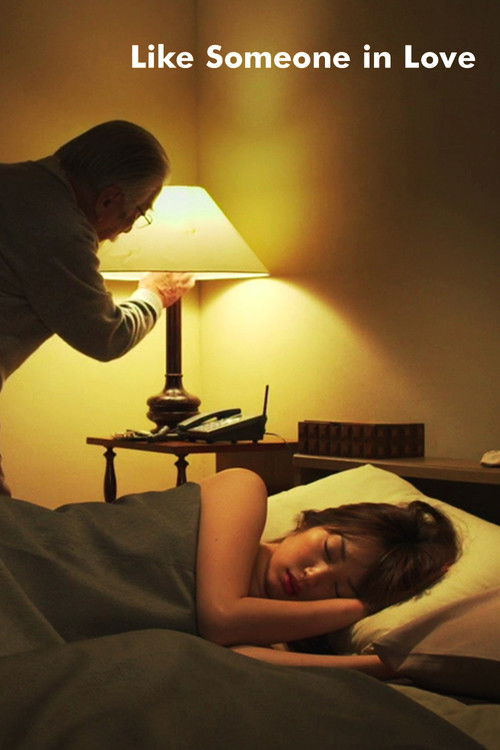 The poster captures a tender moment between a man and woman in a cozy bedroom. Warm yellow tones from the lamp create an intimate atmosphere, while the woman's peaceful expression and relaxed posture suggest comfort and connection. The title "Like Someone in Love" hints at themes of emotional int...