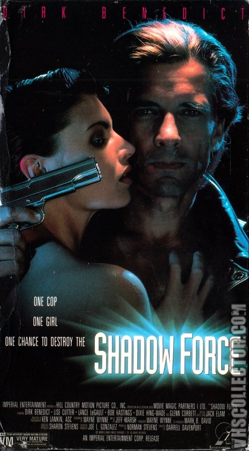 The poster features a dramatic scene with a man and woman in shadowy tones, hinting at a thriller. The man's intense gaze and the woman's tense posture convey suspense and danger. The cool blue and dark colors enhance the ominous mood, suggesting a high-stakes action movie.