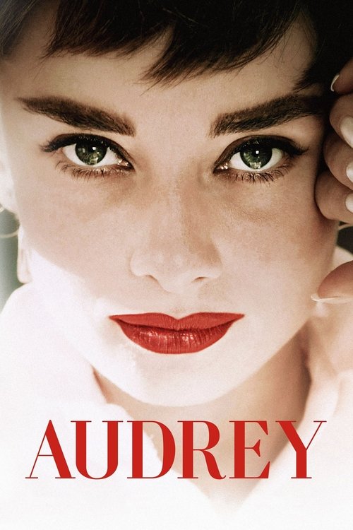 The poster features Audrey Hepburn's striking face, with bold red lips and expressive green eyes. The warm lighting and soft skin tones evoke a timeless, elegant mood. The bold red text "AUDREY" anchors the image, emphasizing the iconic star.