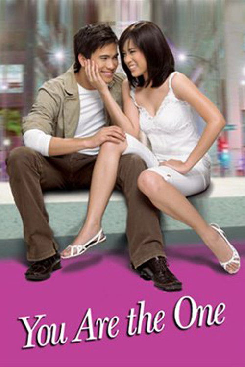 The poster features a romantic couple sitting on a ledge, with the man leaning in to kiss the woman. The woman is dressed in a white dress, while the man wears a beige jacket and brown pants. The background is softly blurred, emphasizing the couple's intimate moment. The overall mood is sweet and...