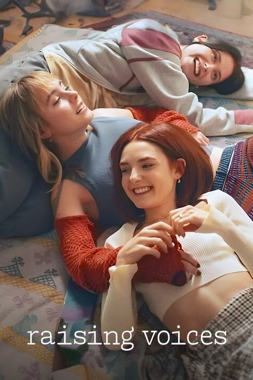 Three young women lie on a cozy, patterned bed, laughing and smiling in a warm, intimate atmosphere. The scene captures a candid moment of connection and joy, reflecting the show's theme of friendship and growth.