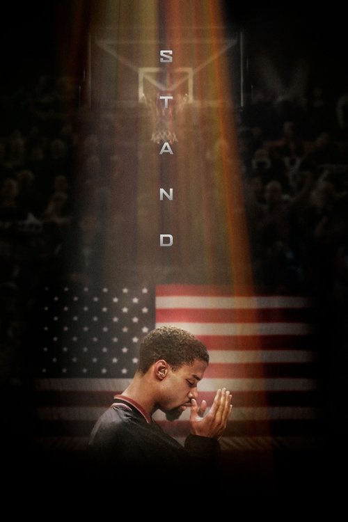 The poster features a young man in a dark shirt, holding a glass of water, with a solemn expression. The background is dark, with a silhouette of an American flag and the word "STAND" illuminated in bright light. The overall mood is reflective and inspiring.