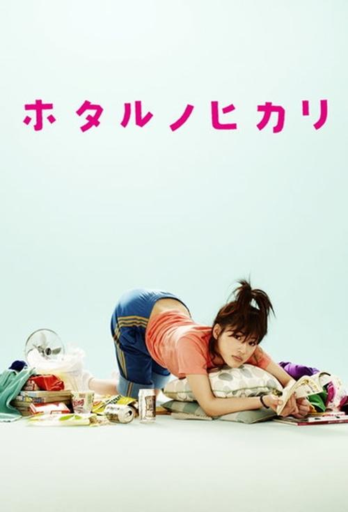 The poster features a young woman with dark hair tied in a bun, lying on her stomach on a white surface. She wears an orange shirt and blue jeans, with her hands resting on her knees. Surrounding her are various colorful objects, including a green bag, a red box, and a purple container, creating ...