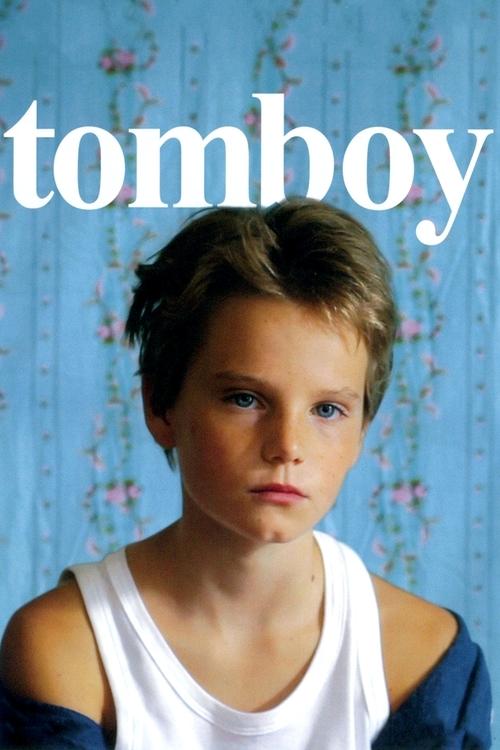 The poster features a young boy with a confident, slightly rebellious expression against a soft blue background. The bold white text "tomboy" dominates the top, emphasizing the theme. The overall mood is one of youthful energy and self-assertion.