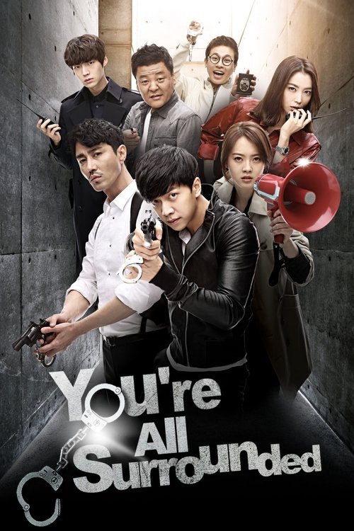 The poster features a group of characters in a dramatic, urban setting with dark, moody lighting. The central figure holds a gun, while others hold various objects like a microphone and a red object, suggesting action and mystery. The title "You Are All Surrounded" is prominently displayed in bol...