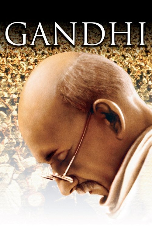 This movie poster features a close-up of Gandhi's serene face, with his glasses resting on his chin. The muted earthy tones and soft lighting evoke a sense of historical gravitas and contemplation.