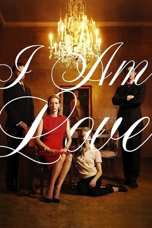 The poster features a romantic scene with a woman in a red dress and a man in a white shirt, both seated on a wooden chair. A chandelier hangs from the ceiling, casting warm light that highlights the couple's joyful expressions. The title "I Am Love" is elegantly written in white script, overlayi...