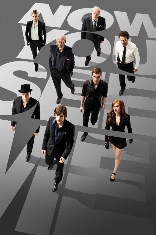 The poster features a group of actors in stylish black suits, some in white shirts, walking confidently against a backdrop of the movie title "NOW YOU SEE ME" in bold, stylized lettering. The overall mood is confident and modern, with a monochromatic color scheme that emphasizes the characters' p...