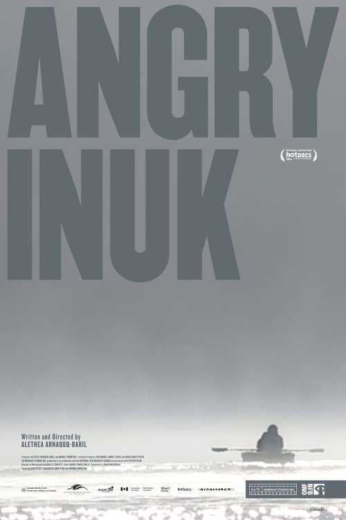 The poster features a stark, monochromatic design with the title "ANGRY INUK" in bold, uppercase letters. The background depicts a desolate Arctic landscape with a lone figure standing on a snowy shore, evoking a sense of isolation and resilience. The muted gray tones and minimalist composition c...