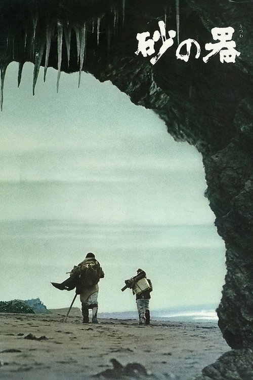 The poster features two figures walking through a vast, icy cave entrance, evoking a sense of isolation and mystery. The muted tones of gray and white dominate the scene, with the dark, textured rock framing the path. The title "砂の暑" (The Sand's Heat) is prominently displayed at the top, suggesti...