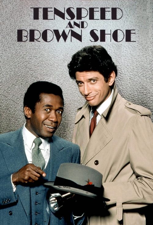The poster features two men in formal attire against a textured gray background. The man on the left wears a blue suit with a light green tie, while the man on the right dons a beige trench coat and red tie. Both men smile warmly, holding a hat, suggesting a professional yet approachable atmosphe...