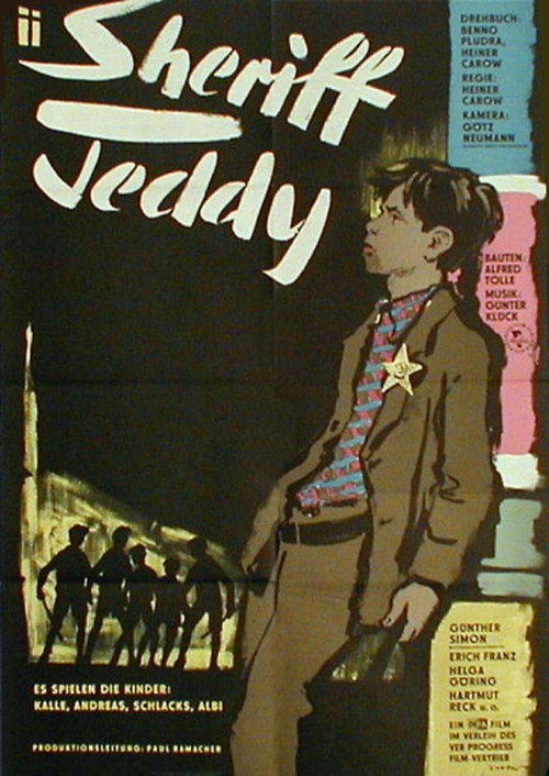 This movie poster features a young boy in a sheriff's uniform with a star emblem, standing against a dark, moody background. The muted tones and shadowy figures evoke a sense of mystery and intrigue.